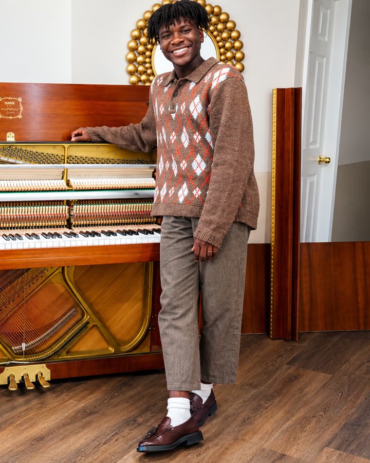 Justin Abraham Paul de pie junto a su piano vertical